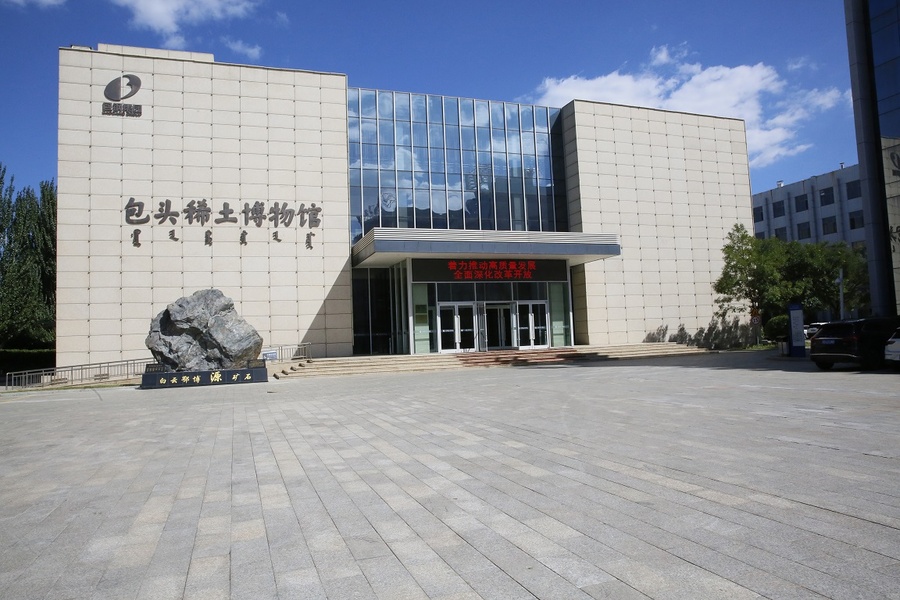 包头稀土博物馆展厅内景，悬挂的矿石装置和环形屏幕展示了稀土从地质到工业的完整脉络