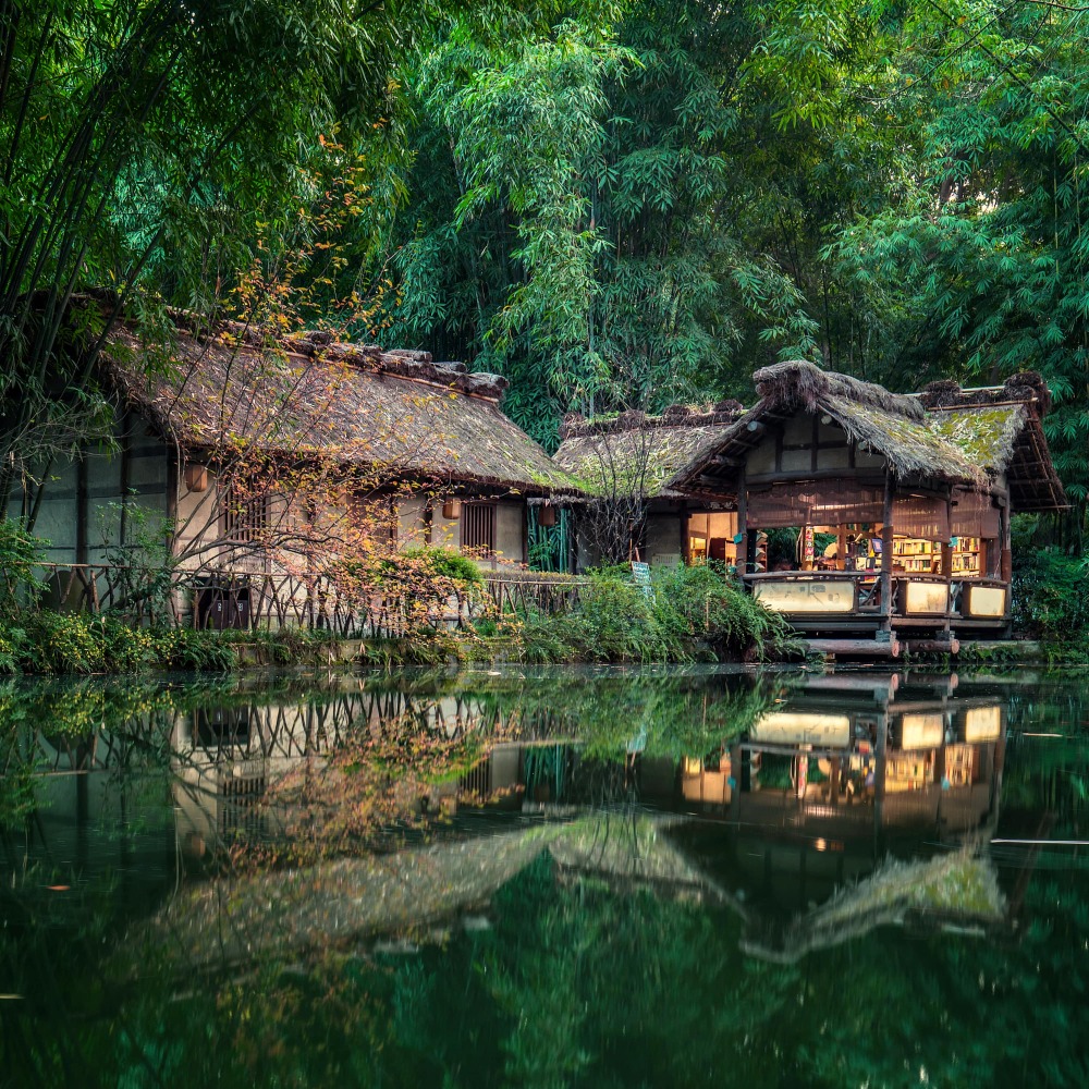 Two traditional thatched cottages are nestled among lush bam