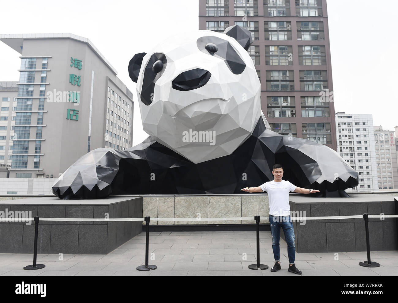 A person stands with arms outstretched in front of a large,