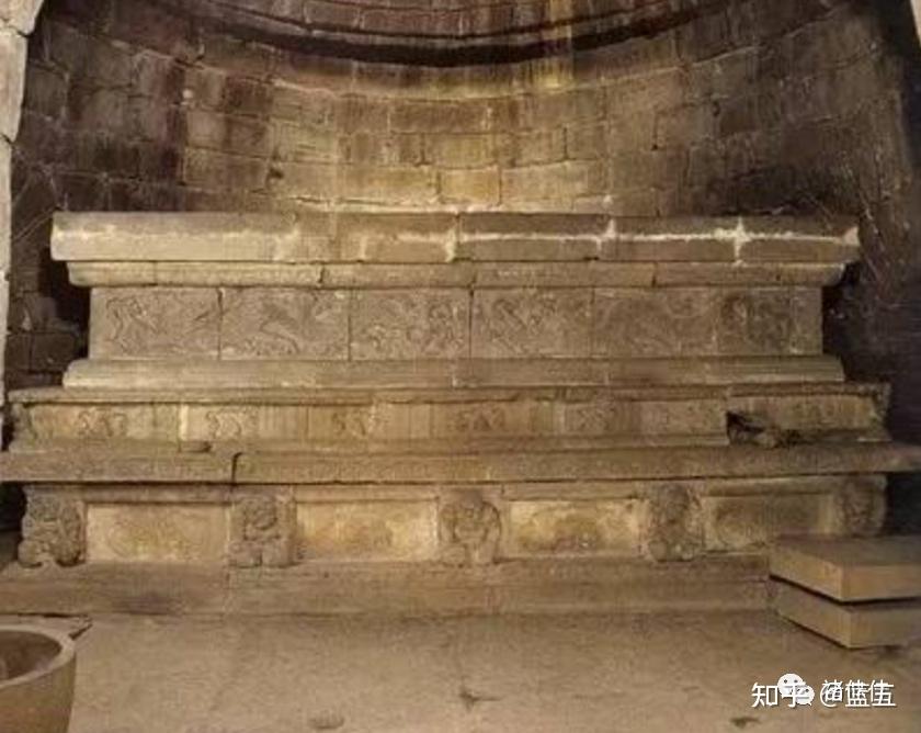 A stone tomb altar with carved dragon motifs is situated ins