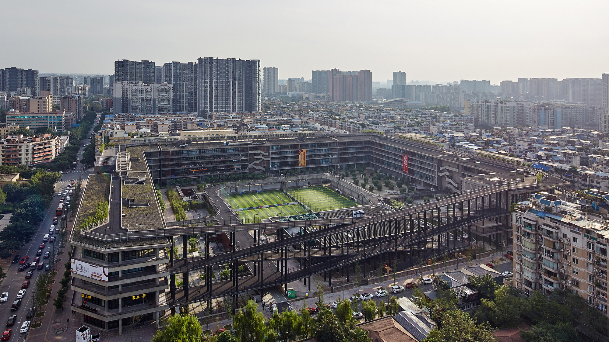 A modern multi-story building with outdoor sports fields on