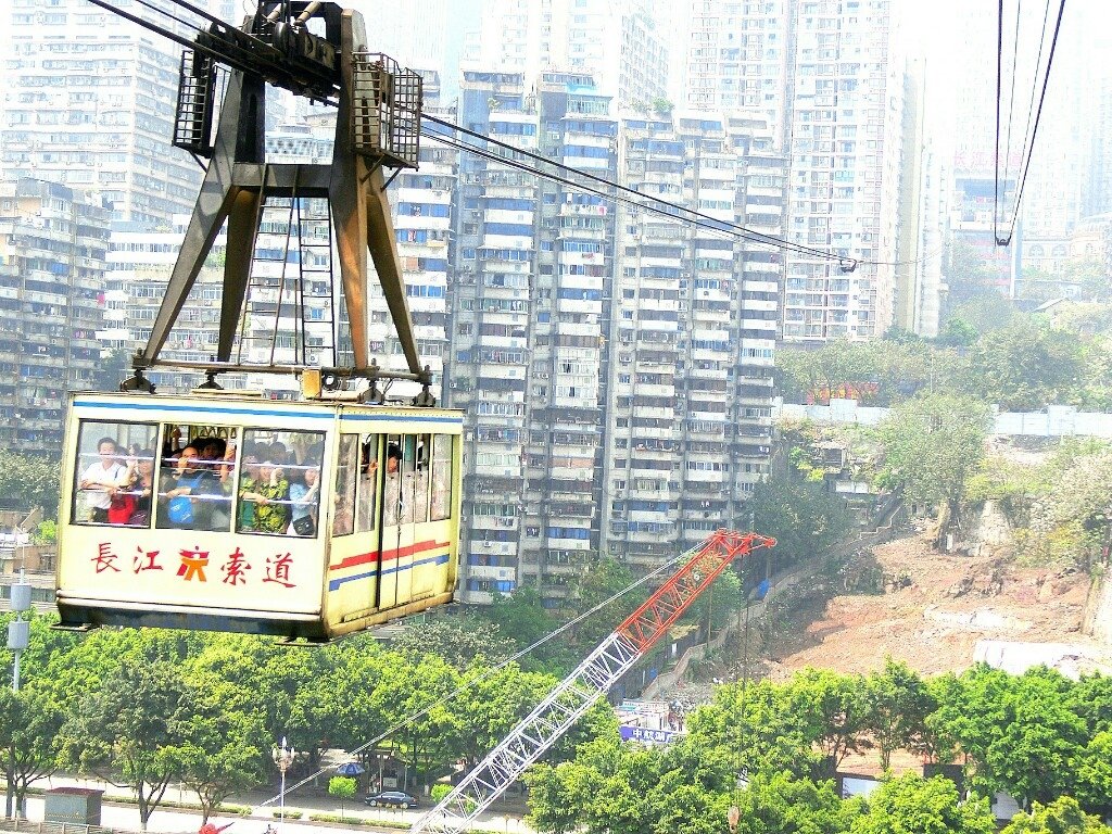 长江索道车厢横跨江面，车厢内乘客与脚下江水形成垂直视角