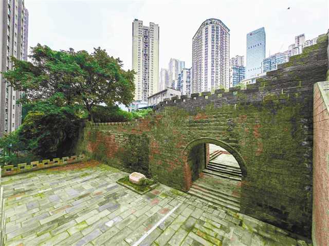 太平门古城墙修复后的全景，墙体沿崖壁延伸，雉堞呈锯齿状排列，后方是现代高楼