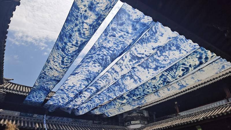 Rows of blue and white tie-dyed fabric are suspended under the roof of the PuZhen Museum courtyard, 