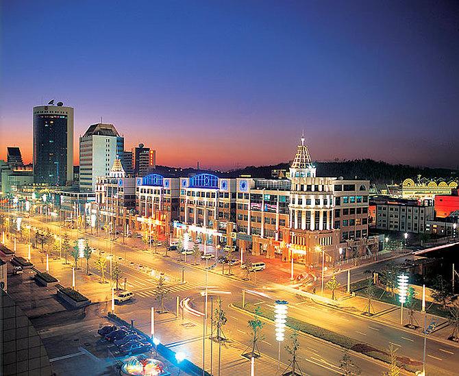 Colorful buildings with bright blue and yellow lighting line a bustling street i