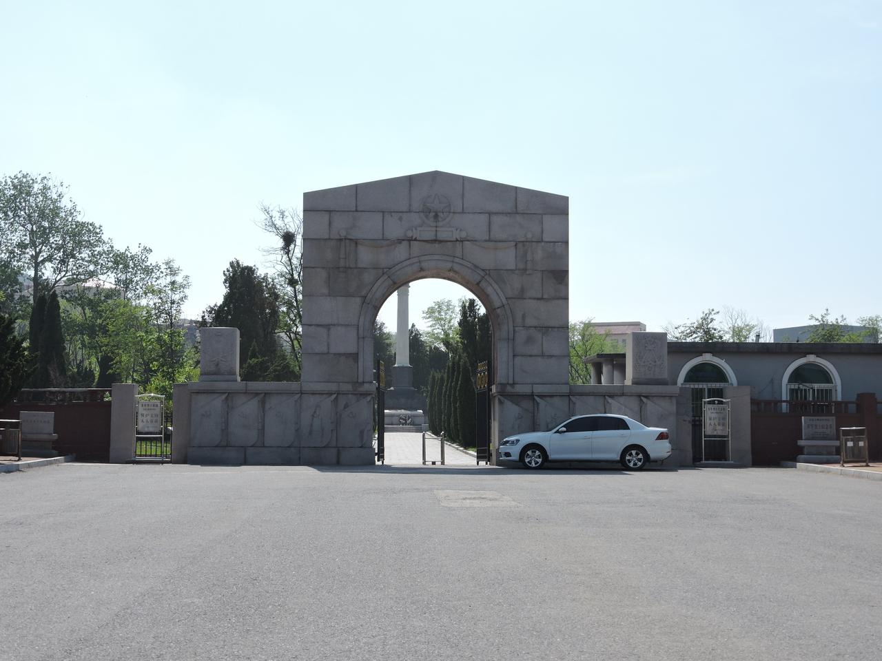 A stone archway with a star emblem and military symbols stands at the entrance o