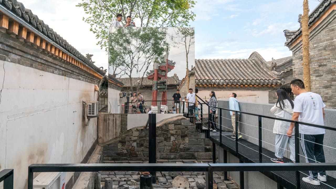 镜面看台反射天空和古城天际线，与周围老建筑融为一体