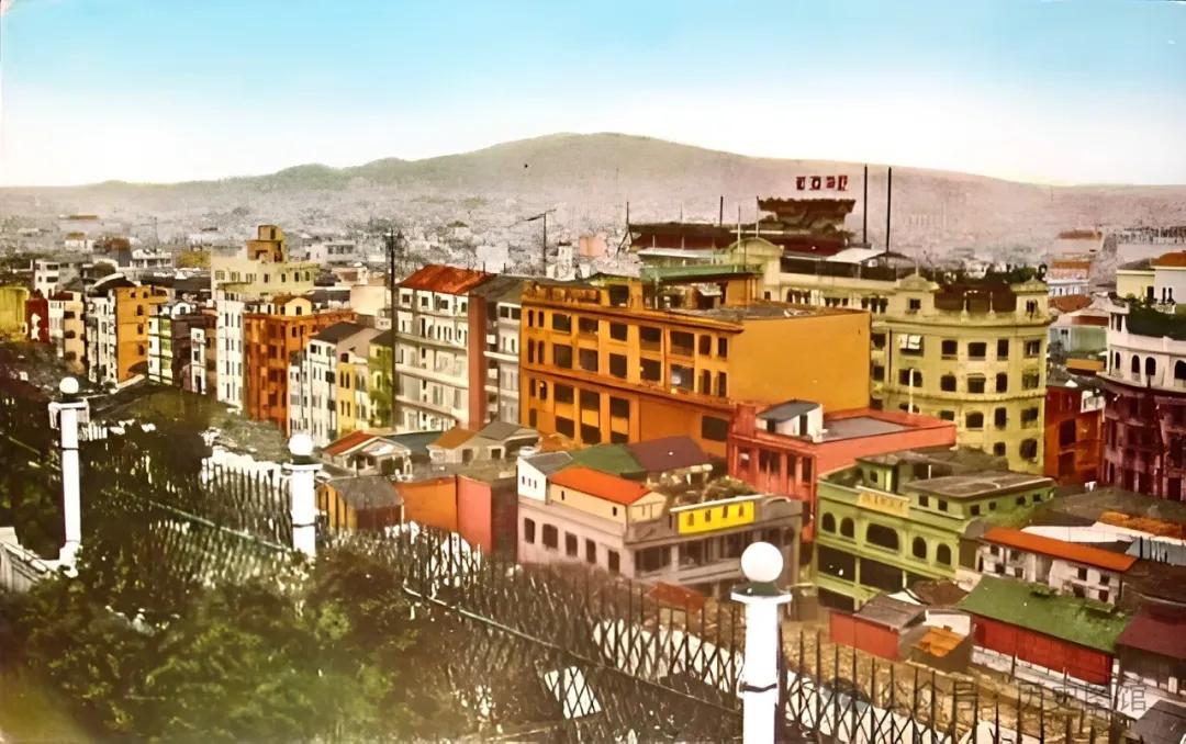 Standing on Guangzhou's rooftop, you can see colorful buildings with a mountain in the background and a large traditiona