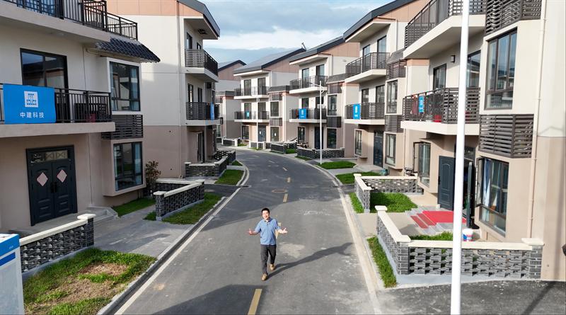 一名男子在广州市中心的一条弯曲的道路上走动，路两旁是现代多层住宅楼，显示出两种不同风格的房屋。