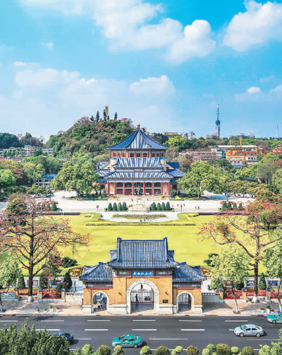 A traditional Chinese-style building with a blue tiled roof stands at the forefront, with a large open courtyard leading