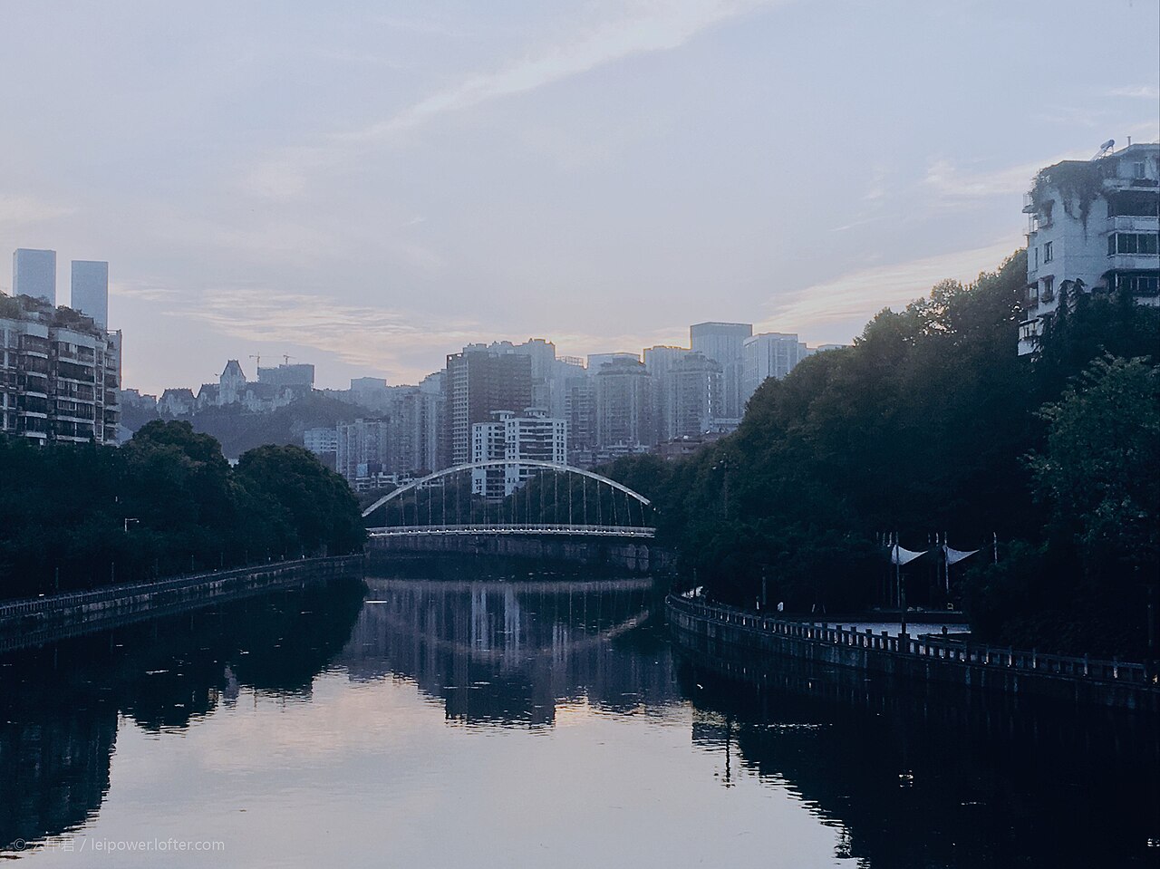 贵阳南明河与城市天际线，白色拱桥横跨河面