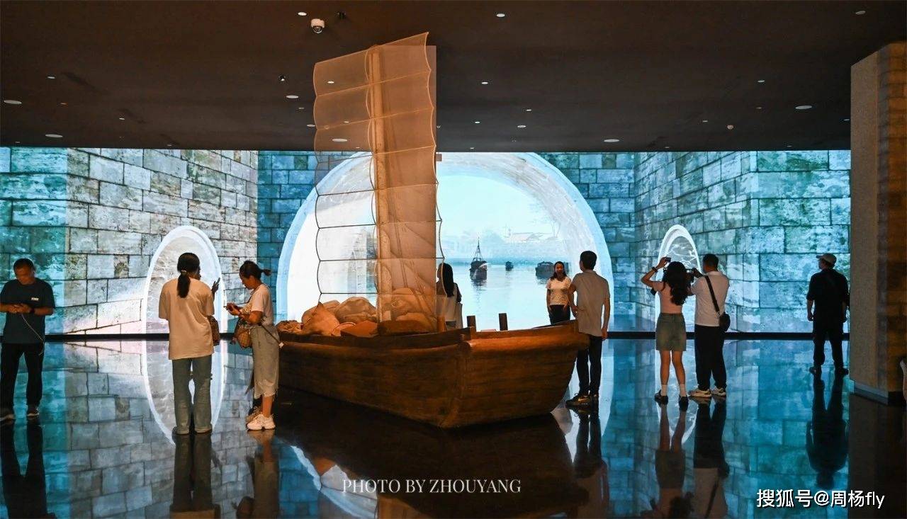 京杭大运河博物馆展厅：参观者观看漕船模型和运河历史展陈