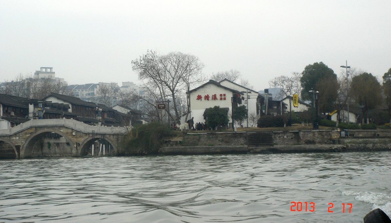 运河上的水上巴士停靠小河直街站，背景是白墙黑瓦的民居建筑群