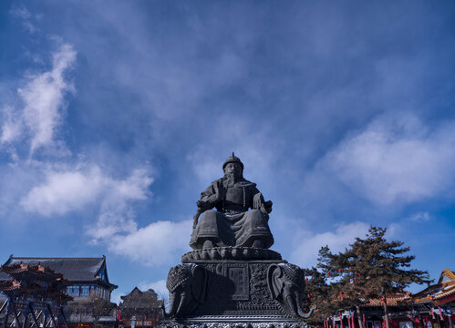 A large bronze statue of Alatan Khan is prominently displayed on a carved stone 