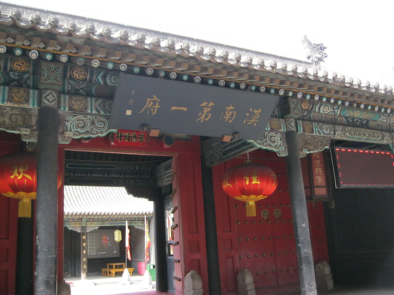 A traditional Chinese gate with intricate carvings and red lanterns, leading to 