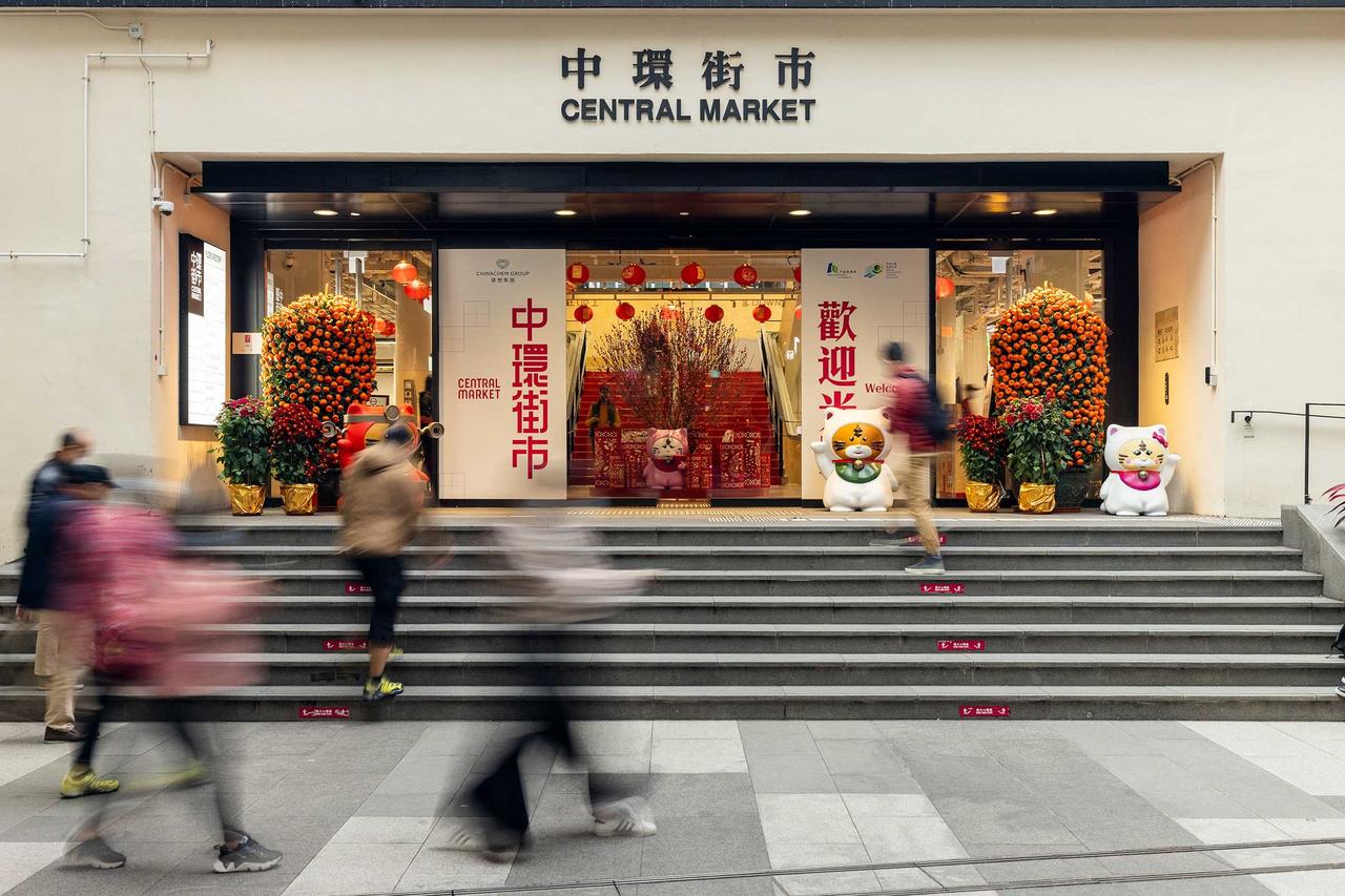 中环街市中庭，钢筋混凝土梁柱结构清晰可见，上方行人天桥连接扶梯系统