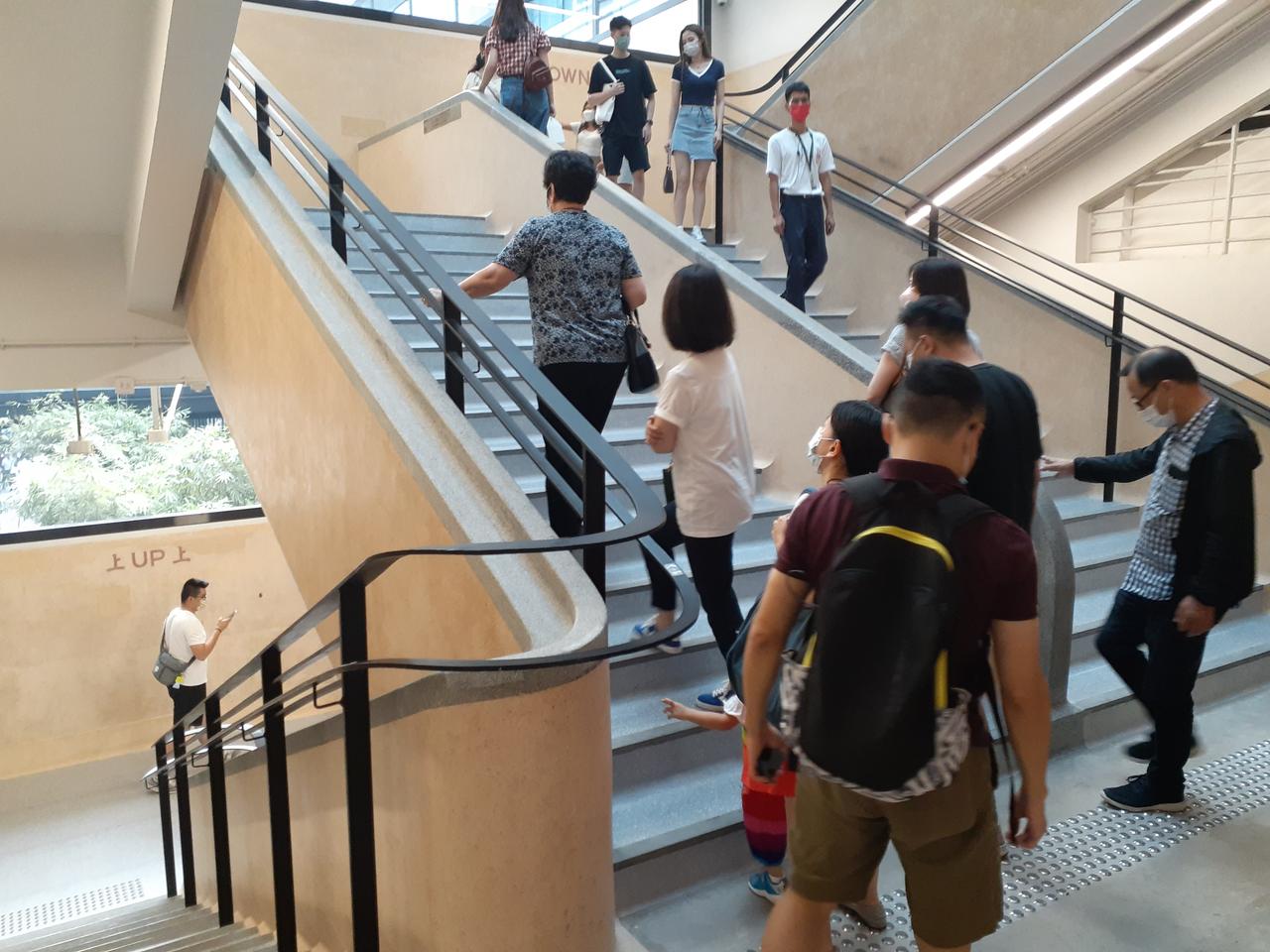 中环街市水磨石主楼梯，地面保留斑驳磨损痕迹，墙面可见"上""落"指示字样