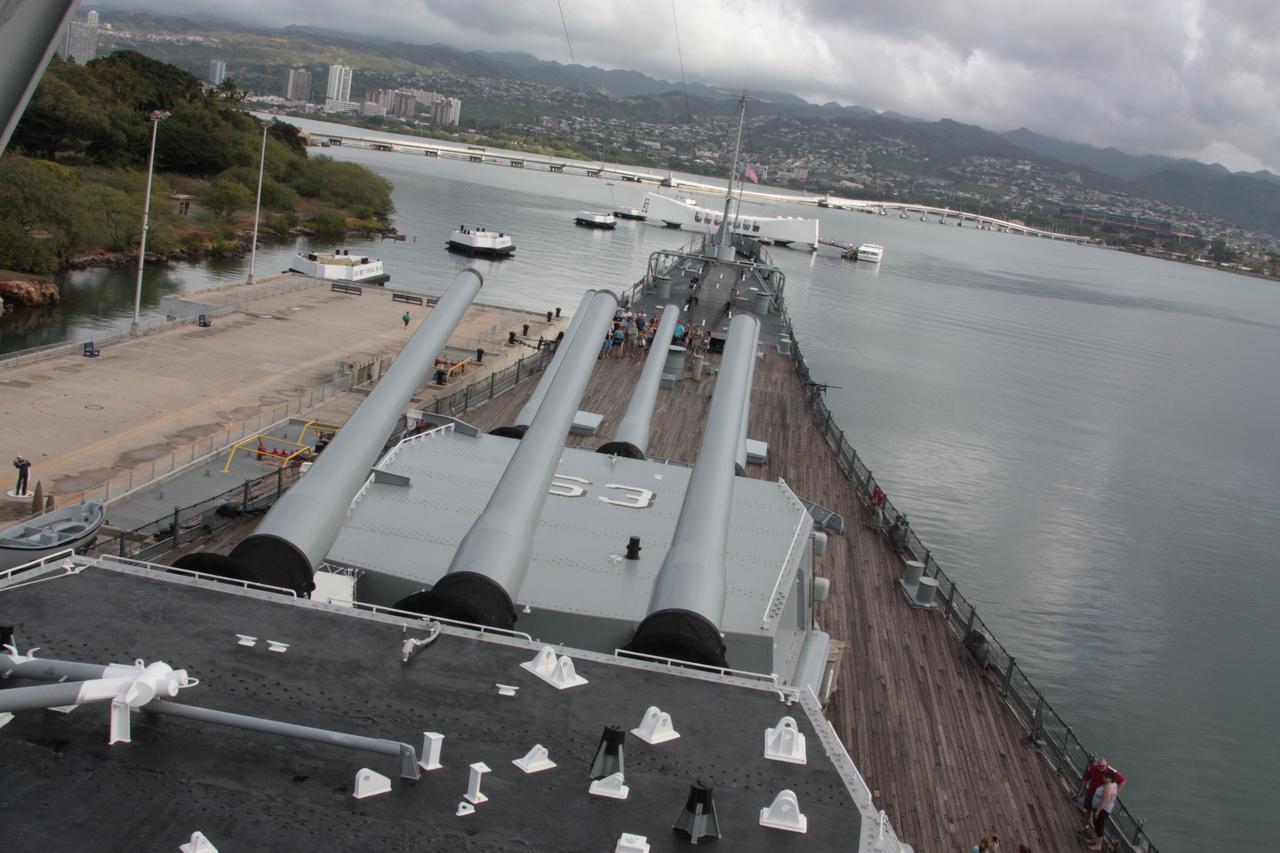 Forward turrets 的 16-inch 炮管指向远方，Arizona Memorial 在水面另一端的背景中清晰可读