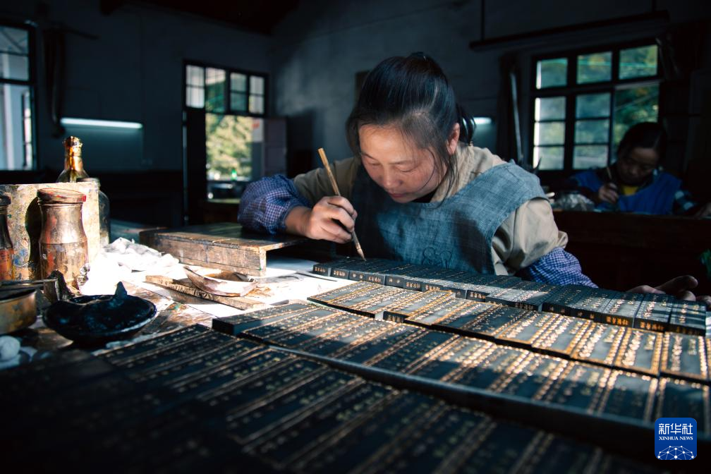 工人手持毛笔在墨锭上描金，墨面文字图案逐渐显现