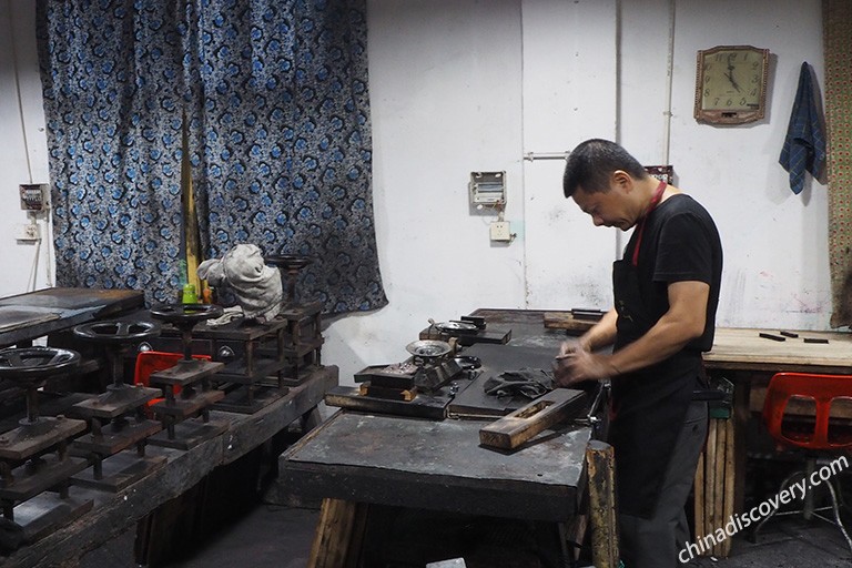 屯溪胡开文墨厂制墨车间内的场景，工人在工作台前翻打墨泥