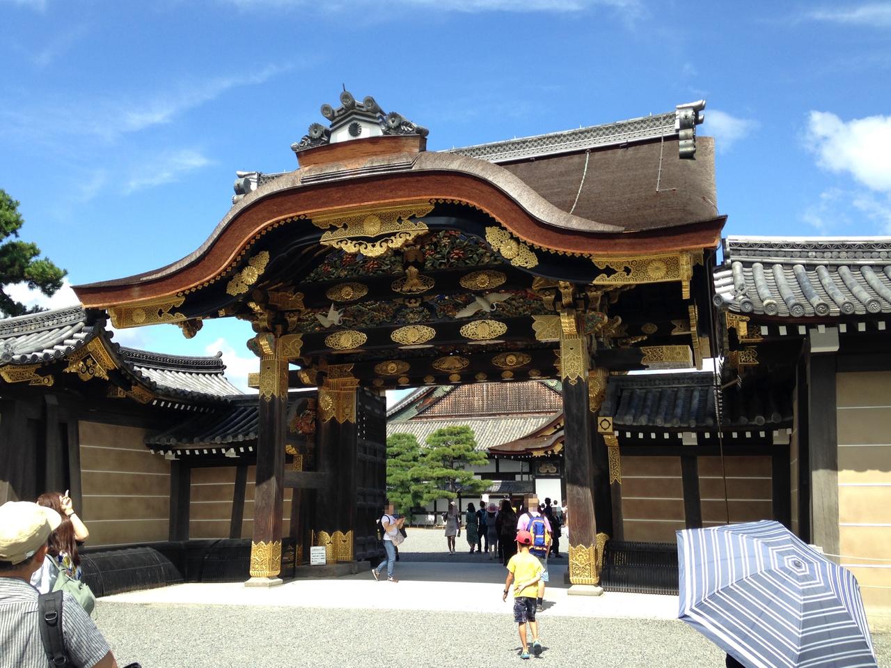 唐门正面，黑漆立柱、金色饰件和密集木雕，弧形唐破风屋顶