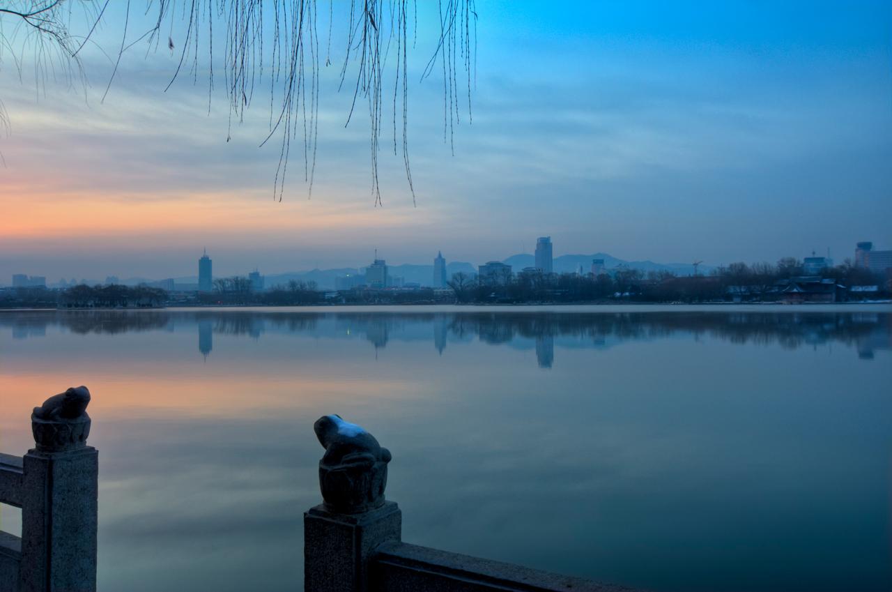 大明湖全景，湖面如镜，南岸可见老城天际线