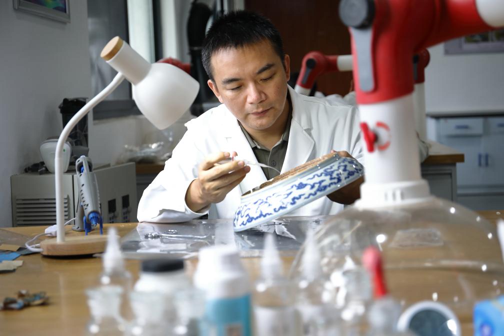 御窑博物院修复研究中心内部，修复师在工作台前对出土碎瓷进行分类整理