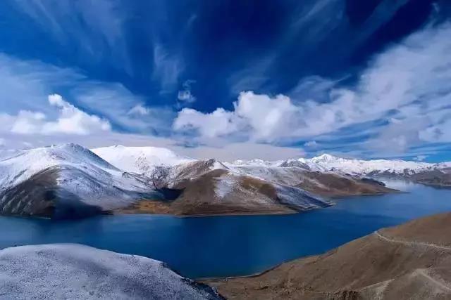 羊卓雍措湖面风光，远处雪山与蓝天倒映湖中