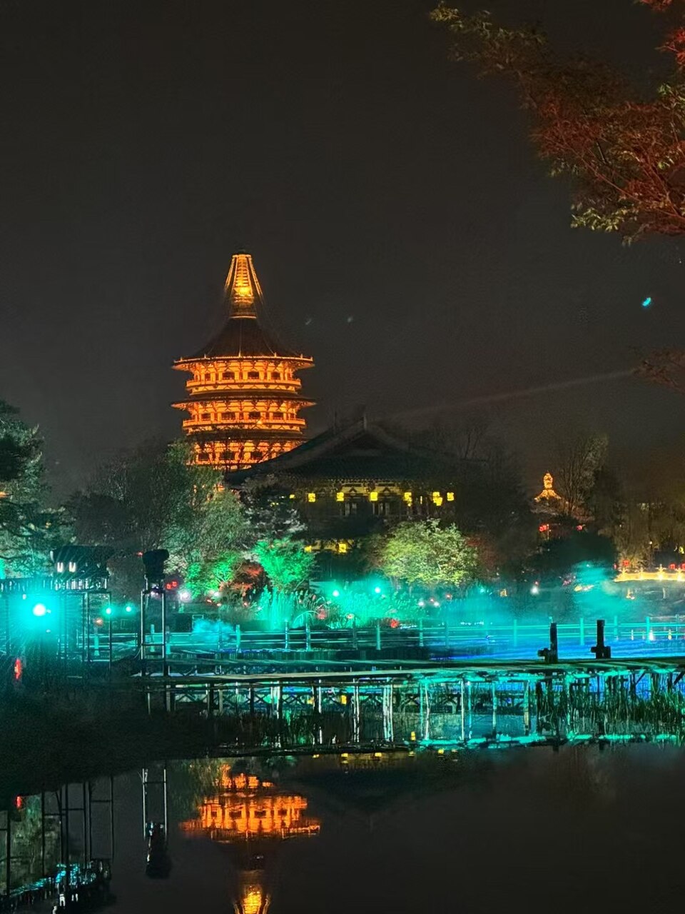 入夜后九洲池灯光倒映，远处天堂塔金色轮廓清晰可见