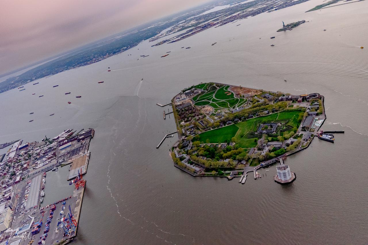 Aerial view of Governors Island at sunset, showing the historic north district and southern parkland