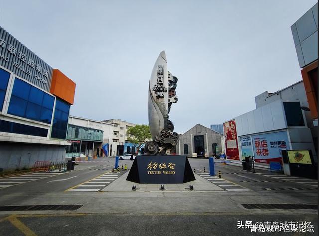 纺织谷入口处的工业风雕塑，齿轮与纺织梭造型暗示园区从纺织工业转型而来