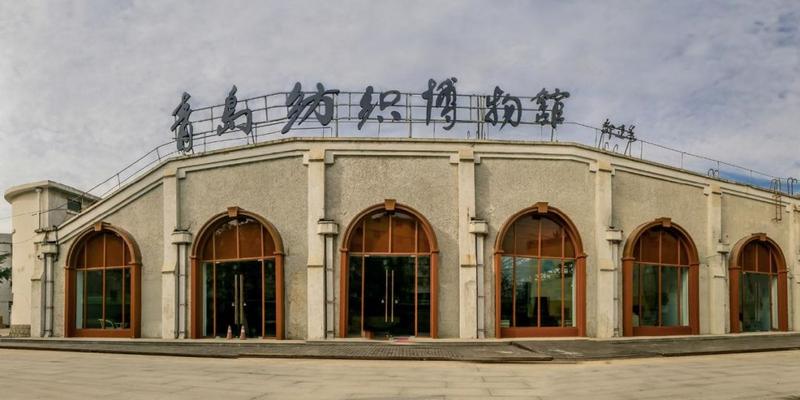 青岛纺织博物馆入口建筑，弧形拱廊和深色框架构成工业风格立面
