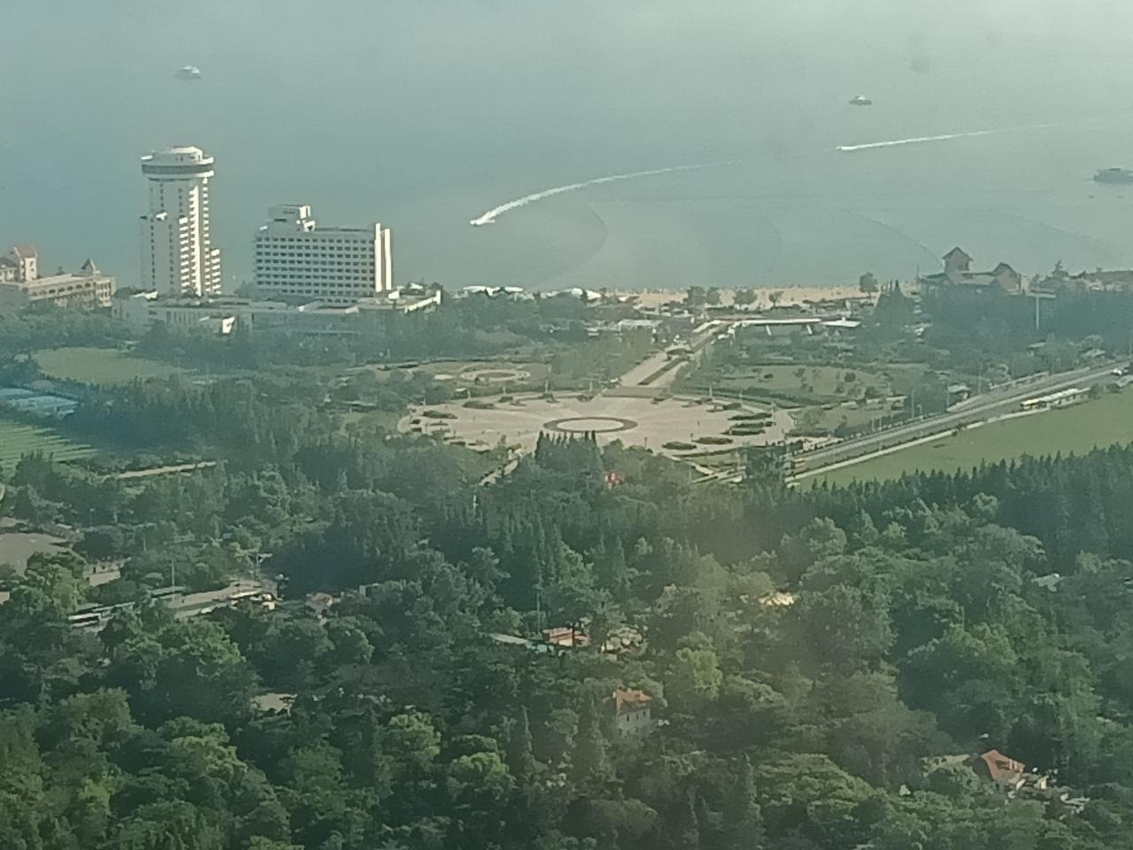 今日汇泉广场南侧的汇泉王朝大酒店和广场空间，远处可见第一海水浴场