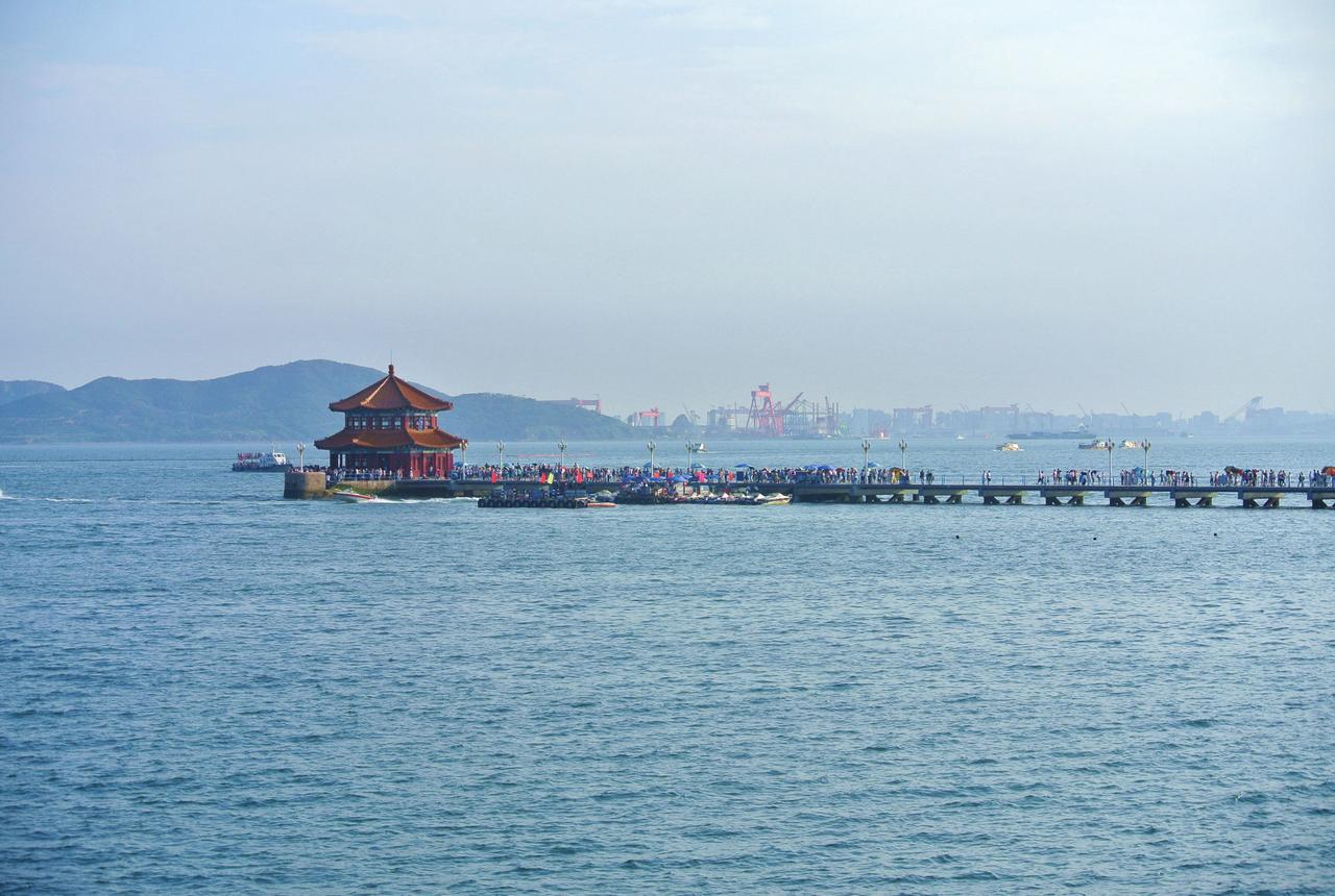 今天的栈桥全景：石砌引堤、透空钢架桥段和尽头的回澜阁