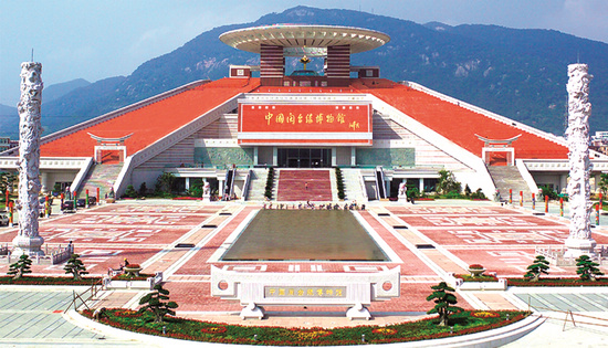 博物馆全景：在西湖边远眺，红砖建筑与金色和平莲倒映在广场水池中