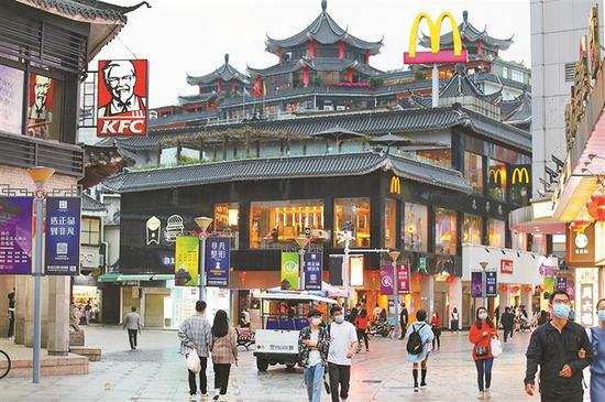 东门步行街夜晚的商业景象，霓虹灯与传统风格建筑并置