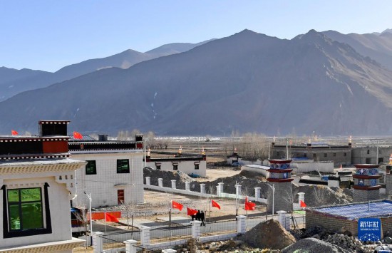 日喀则郊区新建藏式安置点远景，整齐排列的白色房屋与远处山脉