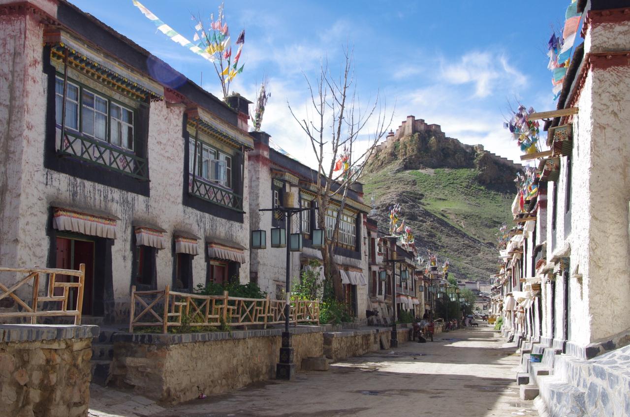 江孜古城藏式碉房街巷，屋顶可见五色塔觉经幡，背景为宗山古堡