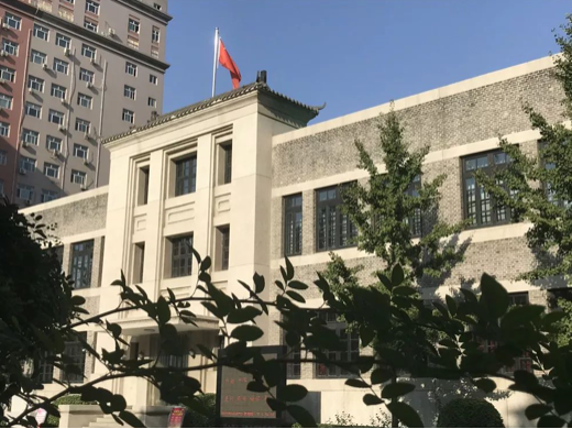 中国人民银行成立旧址纪念馆外景，灰色小楼与现代高楼并立