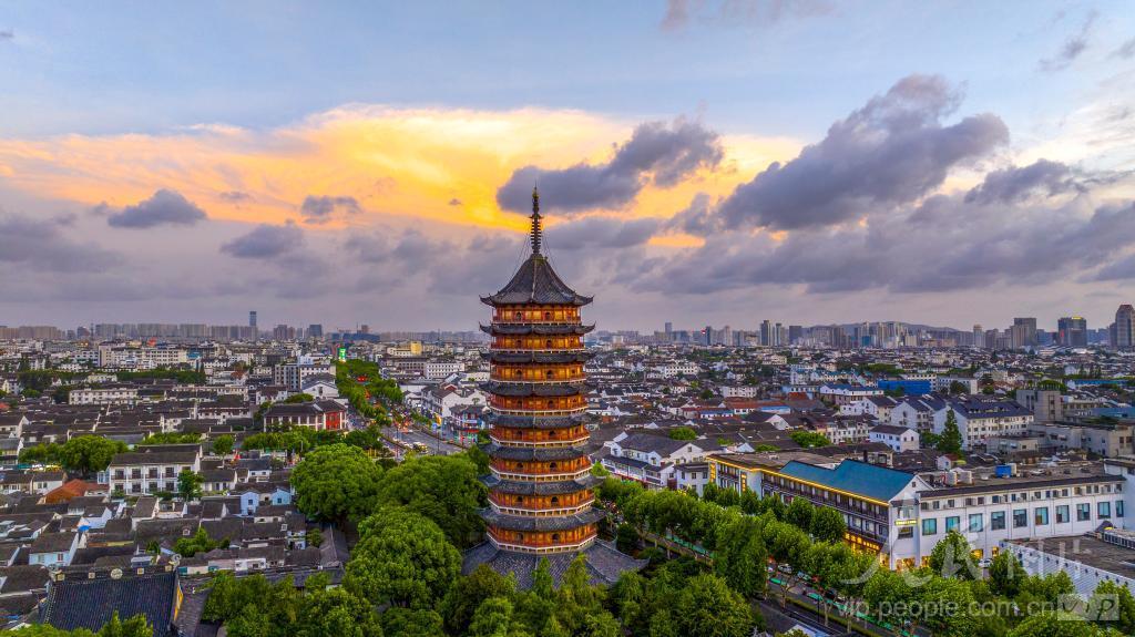 北寺塔在夕阳下从古城屋顶后方升起，天际线上塔身是唯一的制高点