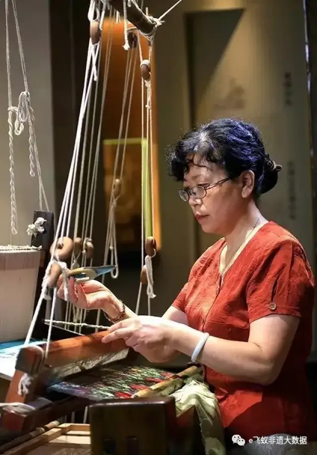 绣娘操作传统花楼织机，两人上下配合才能织出花纹