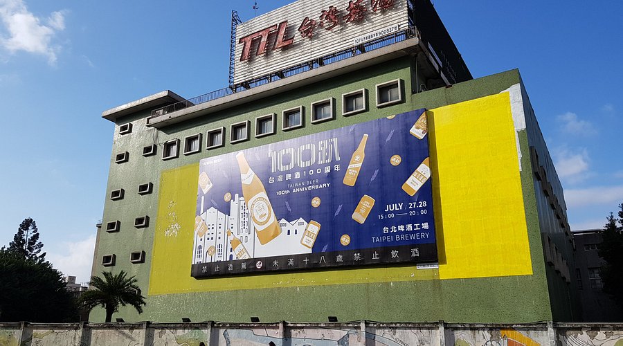 建国啤酒厂外观，红砖厂房与银色贮酒罐