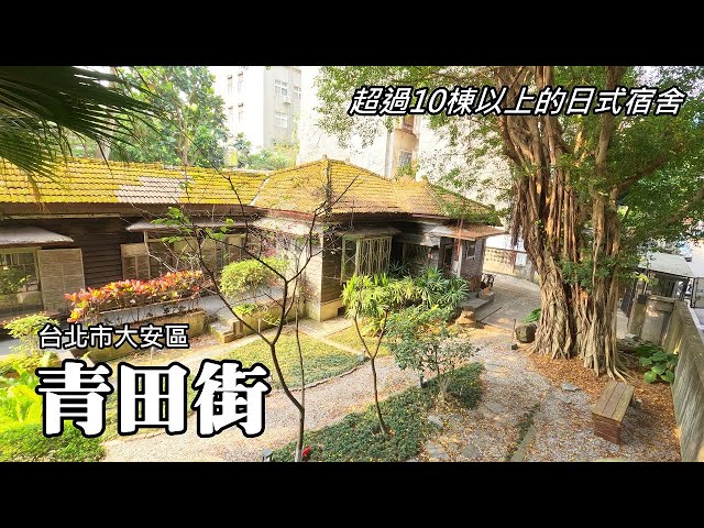 A traditional wooden Japanese-style dormitory is situated in a lush, green garde