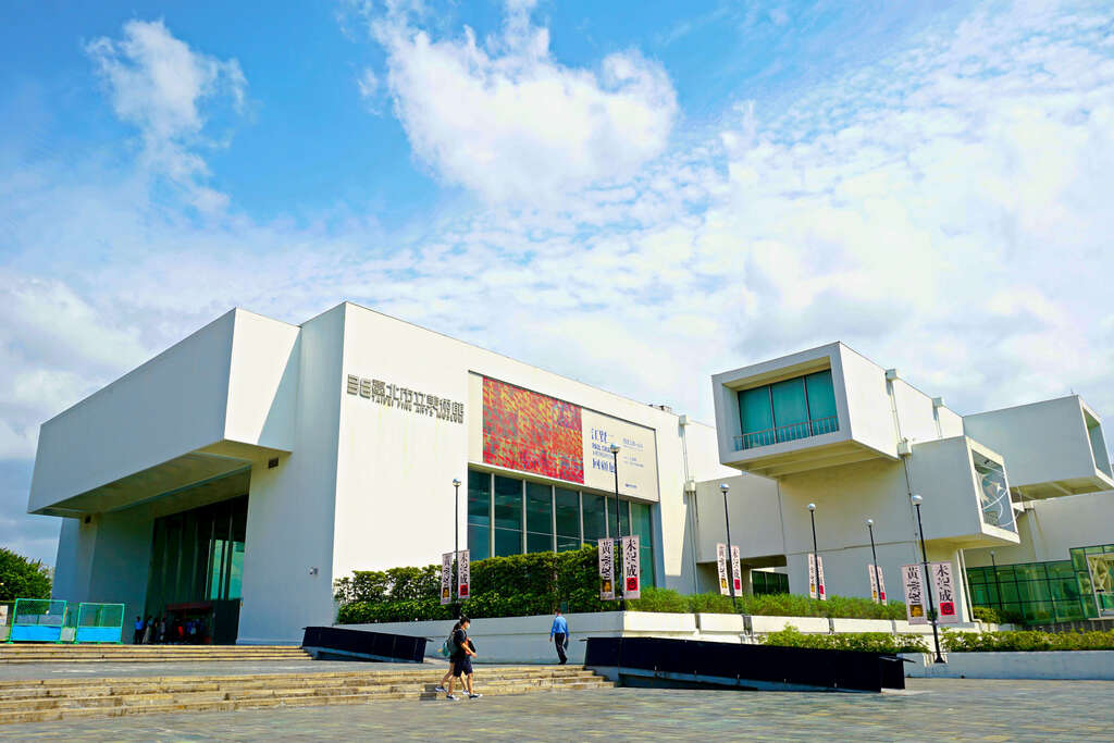 A modern white building with geometric protrusions, large glass windows, and ban