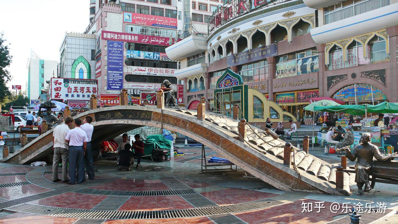 二道桥大巴扎路口街景，远处可见装饰性天桥和逛街的市民