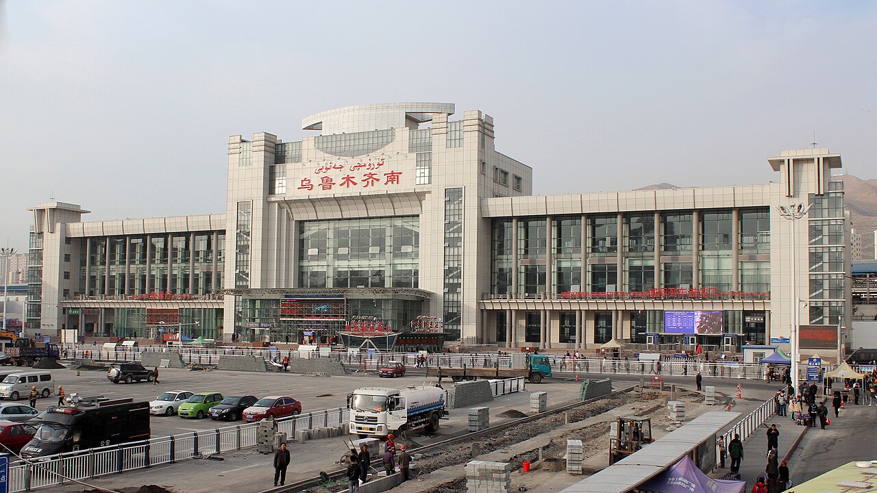 乌鲁木齐南站站房和站前广场，旅客和车辆在站前活动