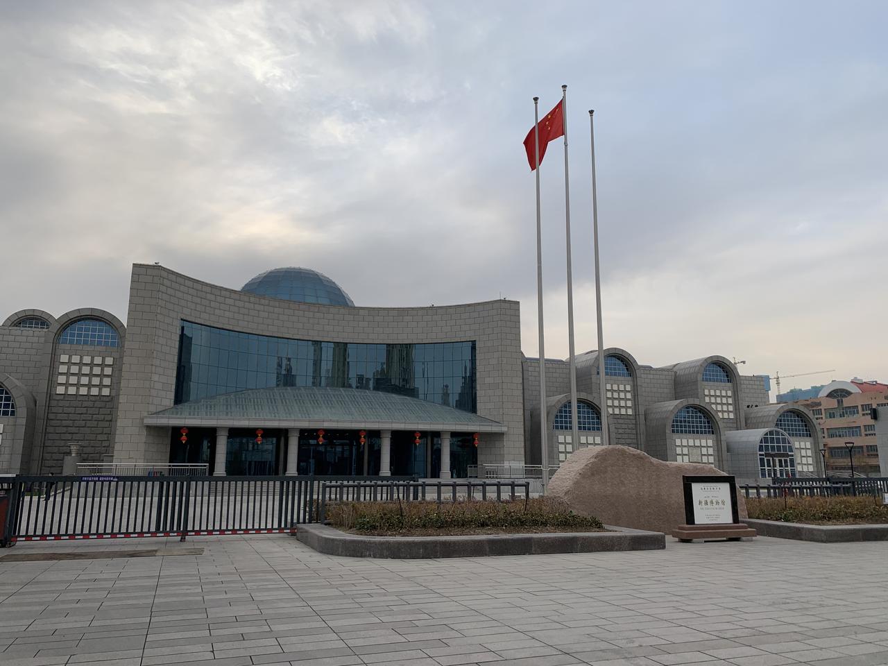 新疆博物馆外景，现代风格的弧形建筑和蓝色玻璃幕墙