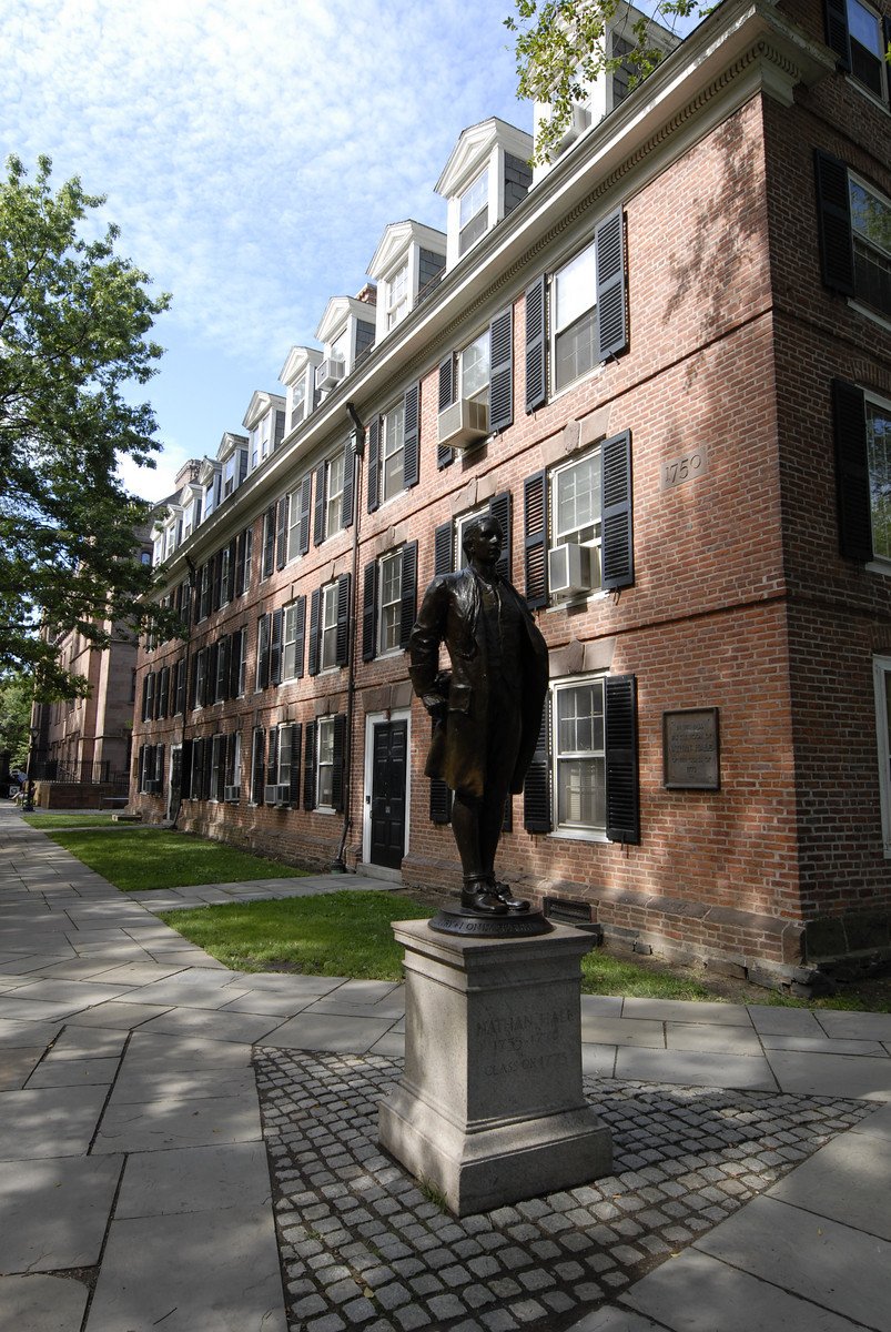 Nathan Hale statue in front of Connecticut Hall, with the building's red brick facade and gambrel roof visible in the background