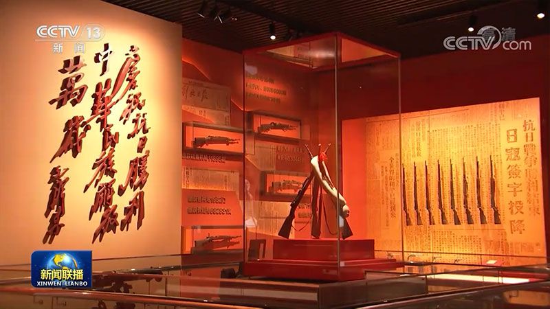 展厅内陈列的革命文物展柜，步枪与旗帜陈列在红色背景中