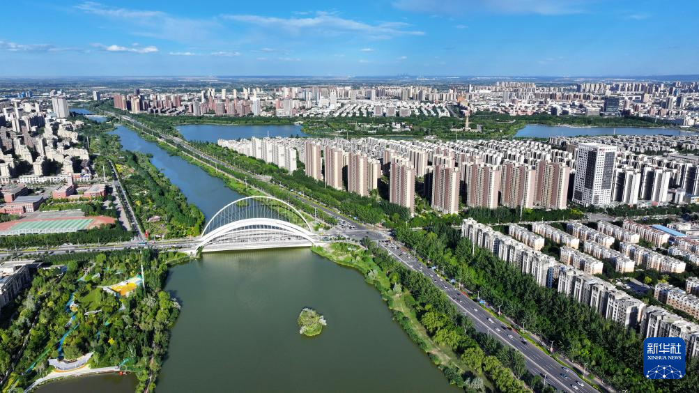A panoramic view of a city with a river flowing through, a modern bridge with an